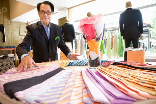 Preview: Elevated View Of A Shop Assistant Adjusting Samples Of Ties On Display While Posing For The Camera.