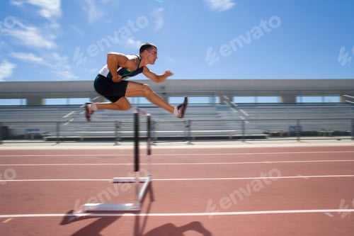 Preview: Blurred Motion Shot Of Male Athlete Jumping Over A Hurdle In The Race On Running Track