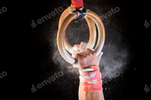 Preview: Detailed Shot Of Male Gymnast Catching Gymnastic Rings With Chalk Dust On Black Background.