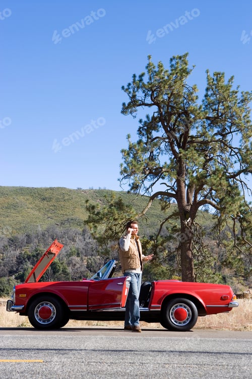 Preview: Vertical Shot Of A Man Besides His Broken Down Car Calls For Assistance Using His Cell Phone On A