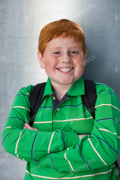 Preview: Vertical Waist Up Portrait Of A Boy In A Green T-Shirt With Folded Arms Smiling At The Camera.