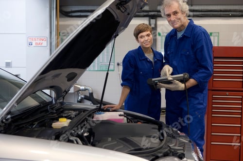 Preview: Senior Mechanic And His Colleague Standing Next To The Open Hood Of A Broken Down Car And Posing