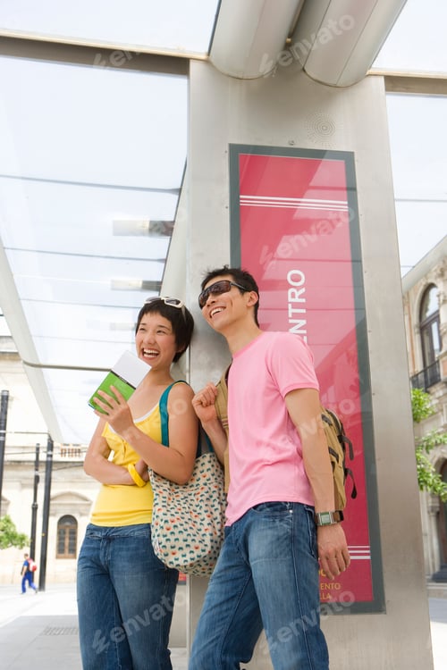 Preview: Vertical Shot Of A Laughing Couple Leaning Against The Wall On A Bright Sunny Day.