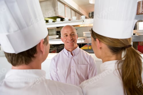 Preview: Elevated View Of A Restaurant Manager Talking To Male And Female Chefs In A Commercial Kitchen.
