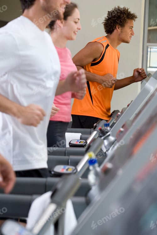 Preview: Side View Of A Woman Flanked By Men In Fitness Clothes Running On Treadmills In The Gym.