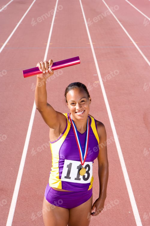 Preview: Young African Female Athlete With Gold Medal Holding Up A Relay Baton In Her Raised Hand At An