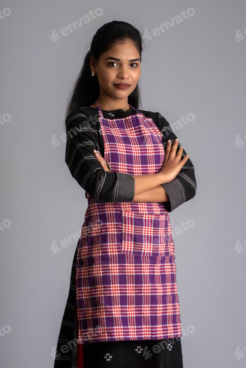 Preview: Portrait Of Indian Woman Chef Or Cook In An Apron On Grey Background.