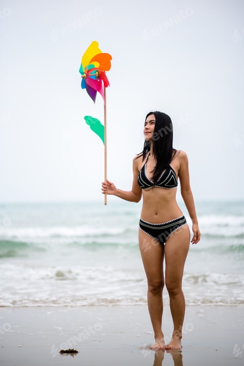 Preview: Woman Holding Pinwheel Toy While Walking At Beach Against Sky