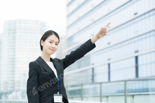 Preview: Asian Young Business Woman In A Suit Pointing Diagonally Above