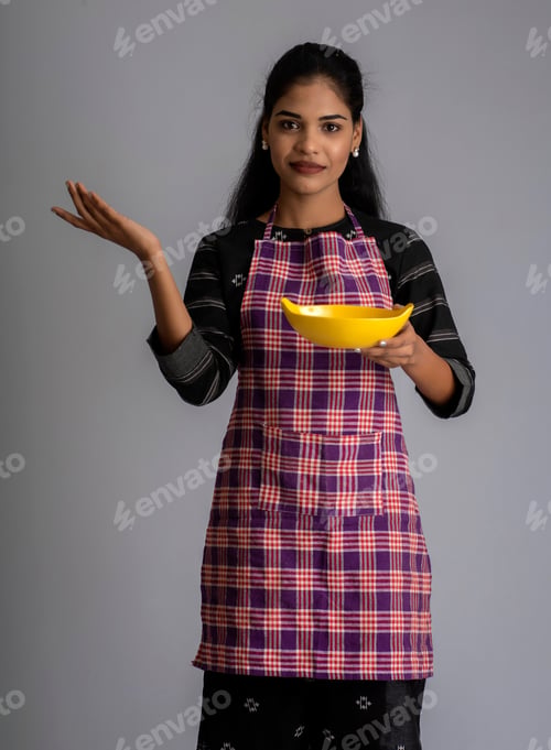 Preview: Young Girl Holding And Posing With Kitchen Utensils Plate And Bowl On A Grey Background