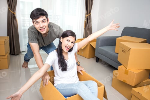 Preview: Happy Asian Couple Is Playing Together With Cardboard Boxes In New House At Moving Day.