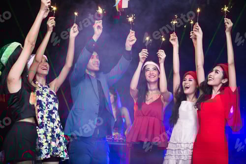 Visualização: Grupo de jovens asiáticos jogando fogos de artifício juntos no Nightcub. Pessoas jogando fogos de artifício com