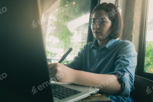 Preview: Young Asian Hipster Woman Writing On Notebook While Working With Laptop Computer In Coffee Shop