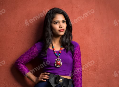 Preview: Beautiful Indian Young Girl Posing Outdoors On Red Wall Background.