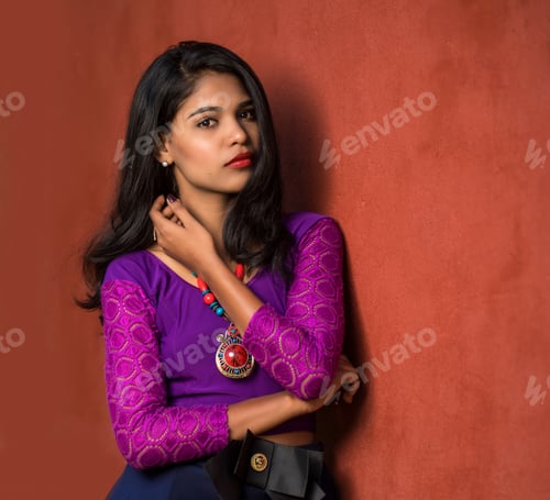Preview: Beautiful Indian Young Girl Posing Outdoors On Red Wall Background.
