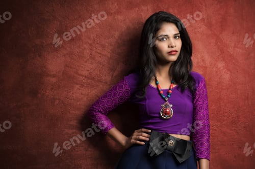 Preview: Beautiful Indian Young Girl Posing Outdoors On Red Wall Background.