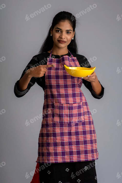 Preview: Young Girl Holding And Posing With Kitchen Utensils Plate And Bowl On A Grey Background