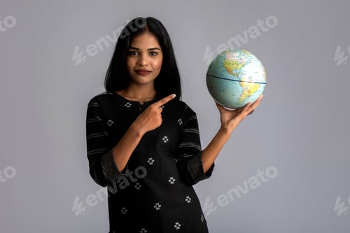 Preview: Young Girl Holding The World Globe And Posing On A Grey Background.