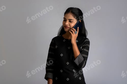 Preview: Young Indian Girl Using Mobile Phone Or Smartphone On Gray Background