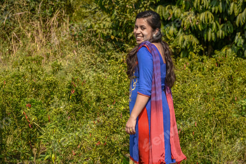 Preview: A Young Indian Woman Farmer Examines Or Observing Chilis In The Farm Field.