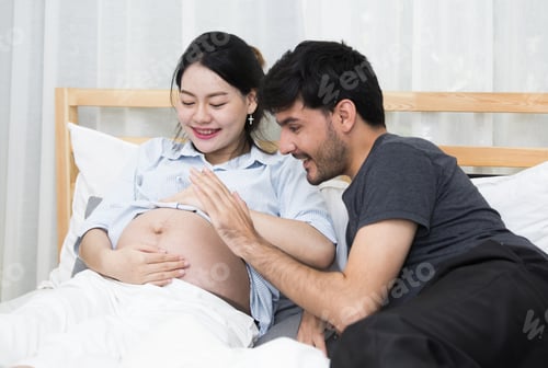 Preview: Expecting Couple Embracing, Caressing Pregnant Belly in Bed