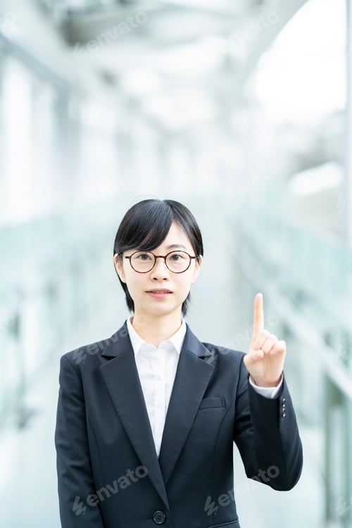 Preview: A Young Woman In A Suit Posing With Her Index Finger Up