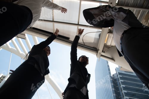 Vista previa: Colleagues Stacking Hands While Standing Against Buildings In City