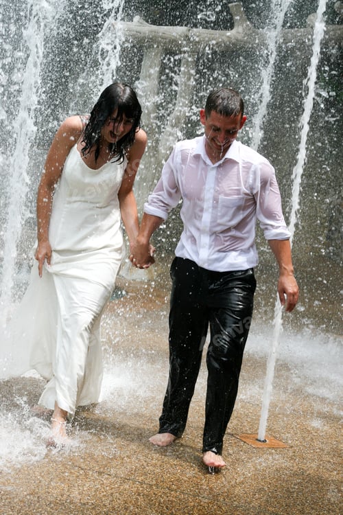 Preview: Bride And Groom Playing Under A Fountain On Their Wedding Day.