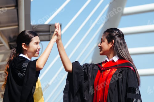 Female Students Celebrate Graduation Success with High Five