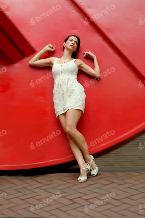 Preview: Life. Young American Lady, Wearing Sleeveless Short Dress, Sandals, Raising Arms, Leaning On Red