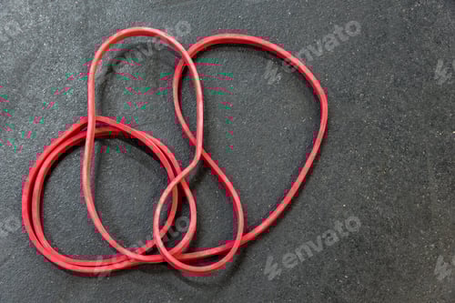 Vista previa: Banda de resistencia roja sobre un suelo de gimnasio negro