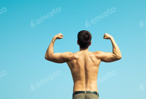 Preview: Young Man Flexing Against Blue Background.
