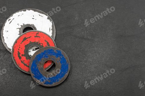 Preview: Closeup Of Three Weight Plates On A Gym Floor, Red, White, And Blue