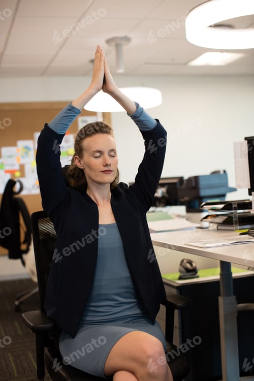 Preview: Businesswoman Practicing Yoga While Sitting On Chair At Office