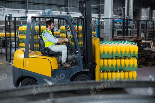 Factory Worker Loading Packed Juice Bottles On Forklift In Factory