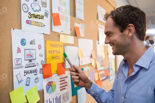 Preview: Male Executive Looking At Bulletin Board In Office