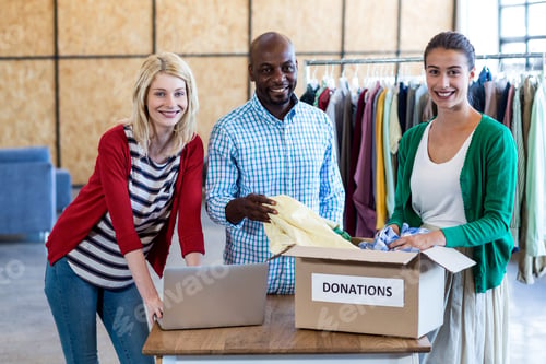 Preview: Portrait Of Colleagues Sorting Clothes From Donation Box In The Office
