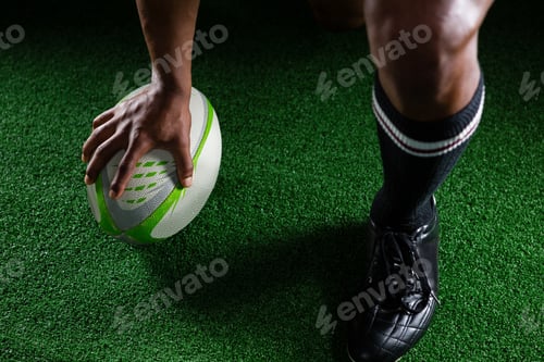 Preview: High Angle View Sportsman Kicking Rugby Ball While Standing On Field