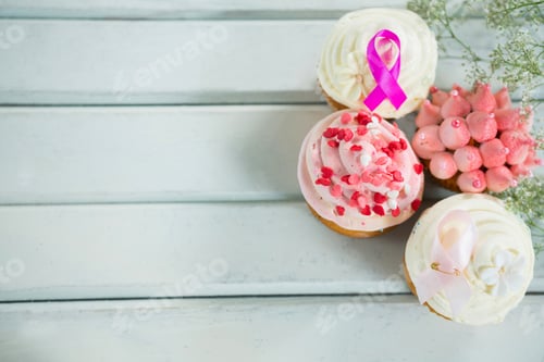 Preview: Overhead View Of Breast Cancer Awareness Pink Ribbons On Cupcakes Over White Wooden Table