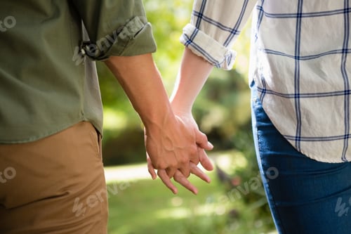 Preview: Mid-Section Of Couple Holding Hands In Garden