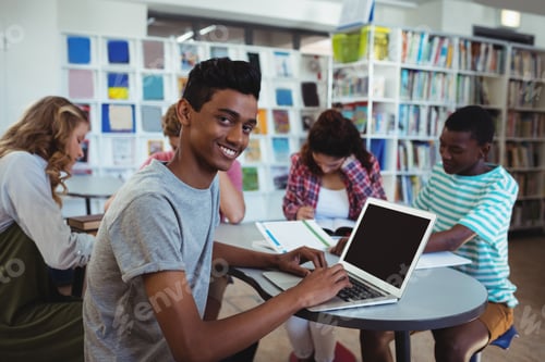 Preview: Smiling Schoolboy Using Laptop With His Classmates Studying In Background At School