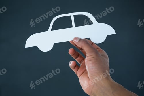 Preview: Hand Of Businessman Holding Paper Cut Out Car Against Grey Background