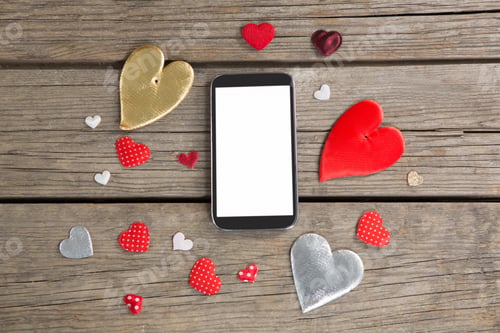 Preview: Mobile Phone Surrounded With Heart Shape Decoration On Wooden Surface