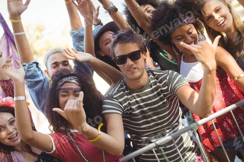 Preview: Happy Young Man Gesturing Shaka Signs While Enjoying With Friends At Music Festival
