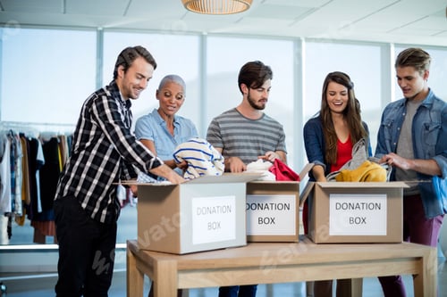 Preview: Creative Business Team Sorting Clothes In Donation Box In Office
