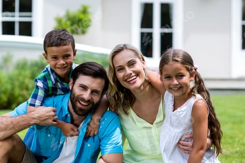 Preview: Portrait Of Happy Family Sitting On Grass At Yard