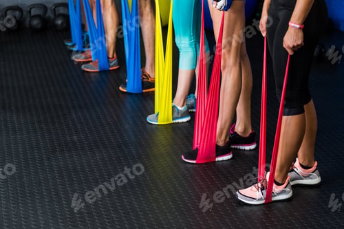 Preview: Low Section Of Athletes Exercising With Resistance Band In Fitness Studio