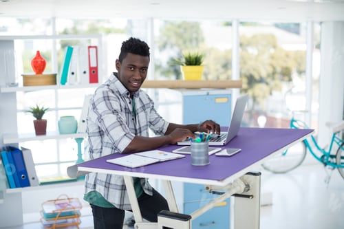 Preview: Portrait Of Smiling Executive Working On Laptop In Office