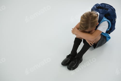 Preview: Overhead View Of Sad Schoolboy Sitting On White Background