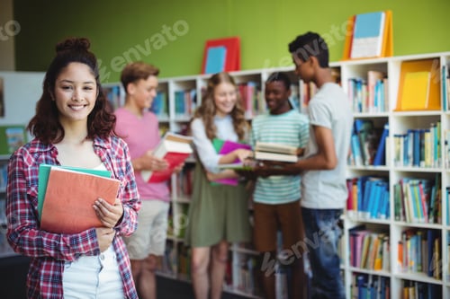 Preview: Portrait Of Happy Schoolboy Holding Book In Library At School